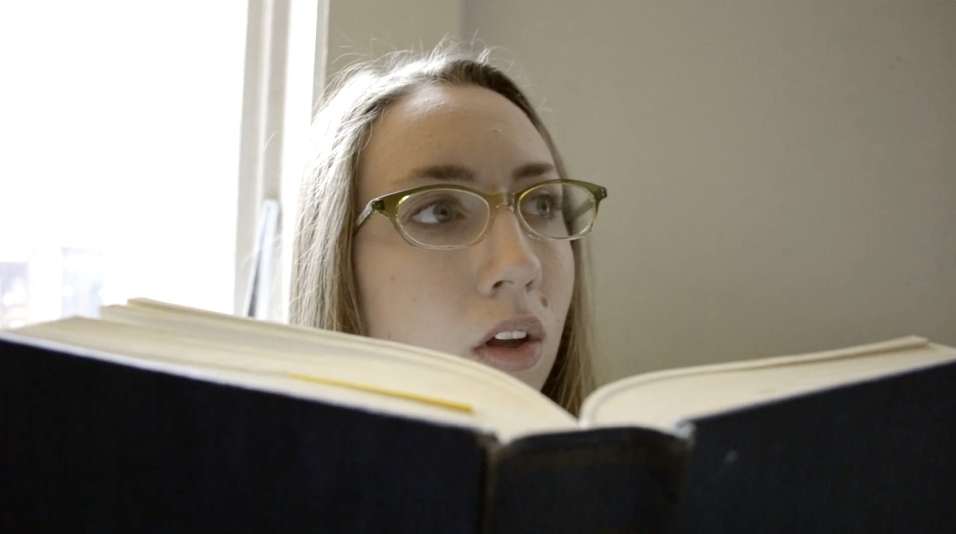 Sill from "Filmmaker Reel". Woman looking over a book